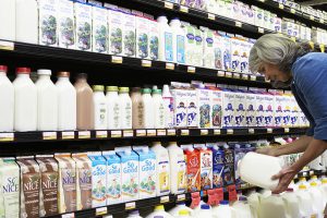 Mature woman reading milk label in supermarket, side view, close-up