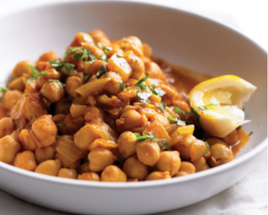 "white shallow bowl with brothy chickpeas and a lemon wedge"