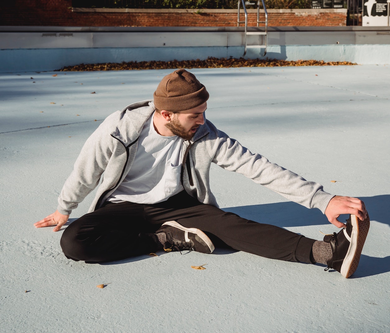 "Man with winter exercise clothes sitting down and stretching his legs"