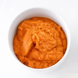 White ceramic ramekin filled with pumpkin puree on a white table.