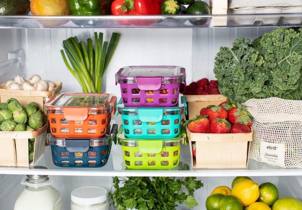 Inside view of a fridge with fresh vegetables and brightly colored containers