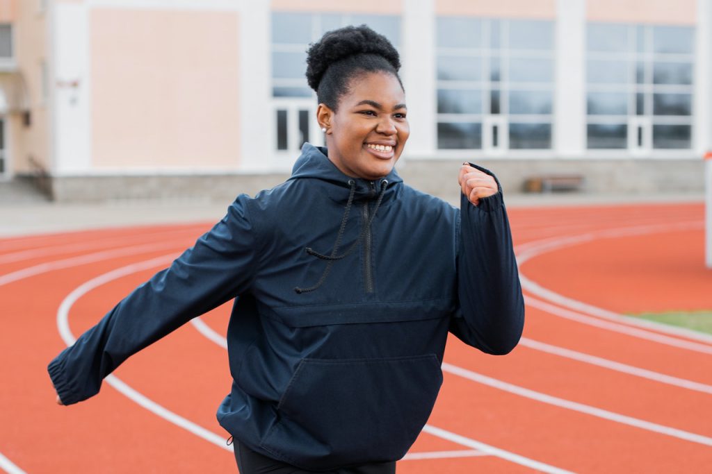 African American woman joyfully power walking on a track.