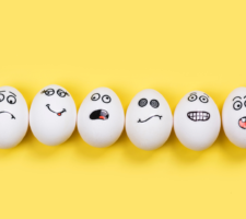Funny eggs with different mood faces on a yellow background.