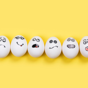 Funny eggs with different mood faces on a yellow background.